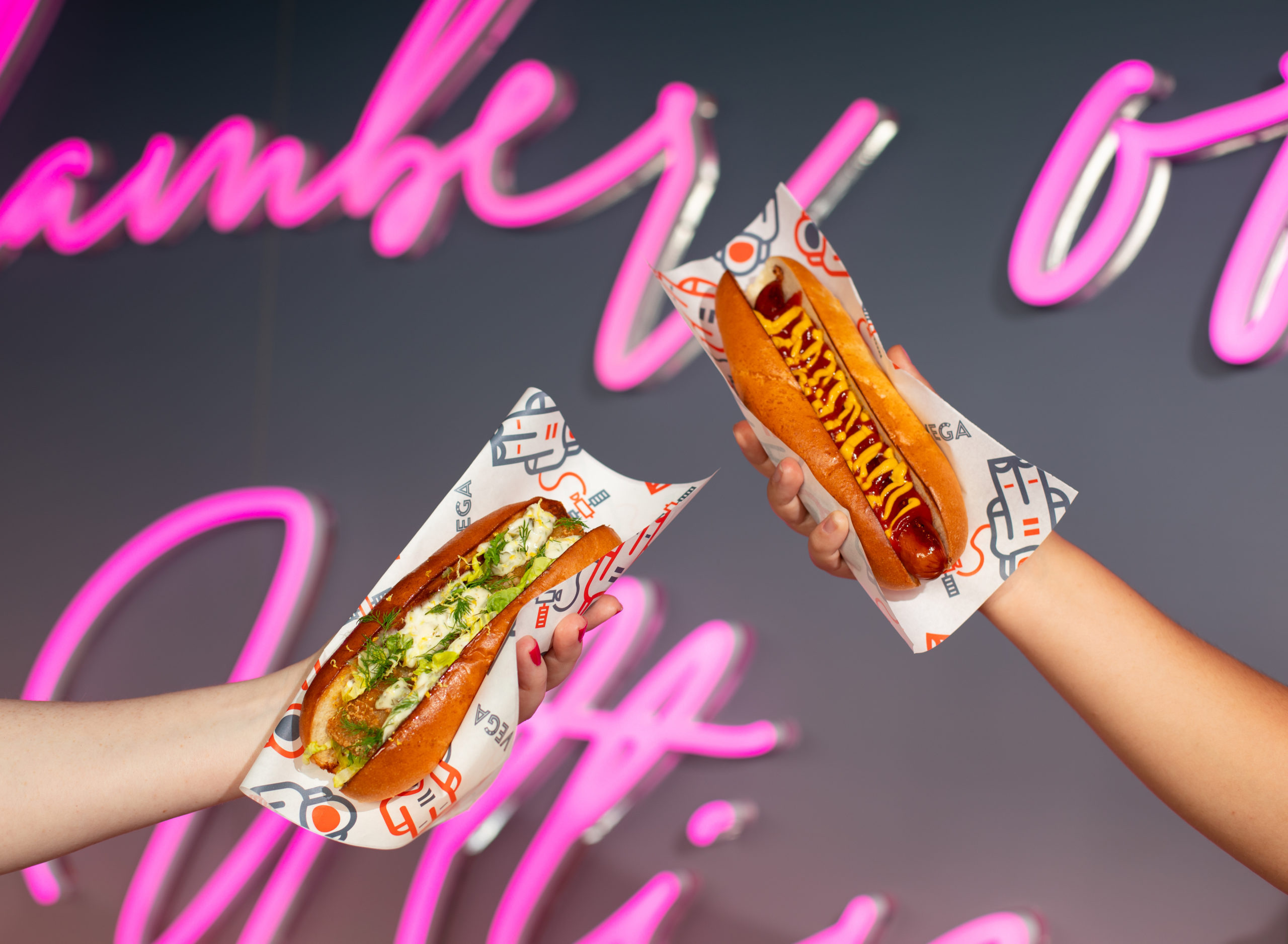 Guests holding two VEGA hotdogs in the air