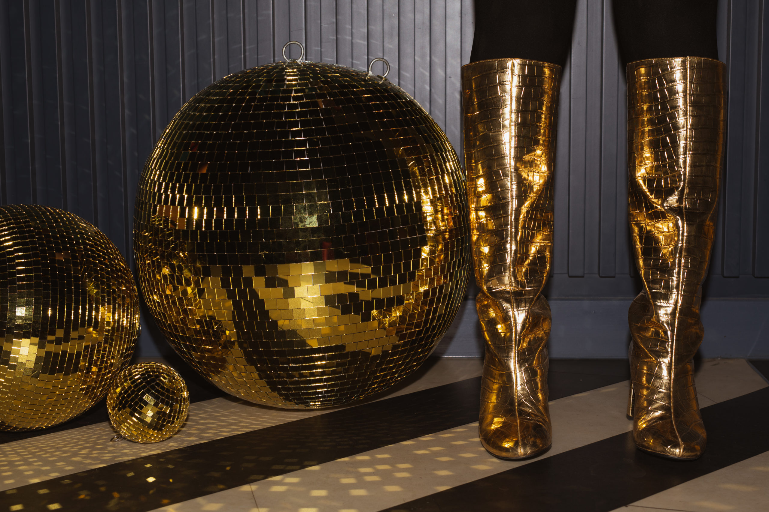 Woman in gold boots next to golden disco balls